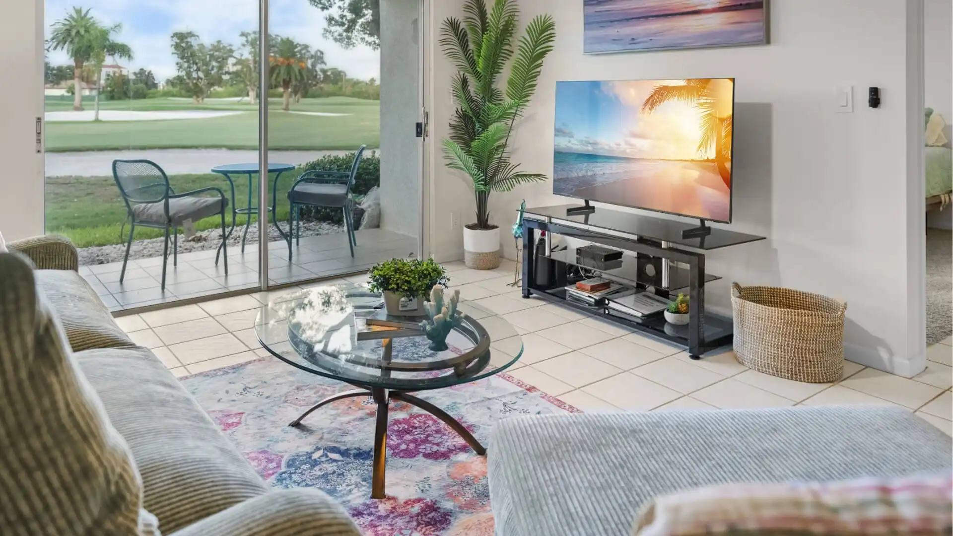 Living room of Isla Bliss Unit 126, a vacation rental in St. Petersburg, featuring modern decor, flat-screen TV, and patio with golf course views.
