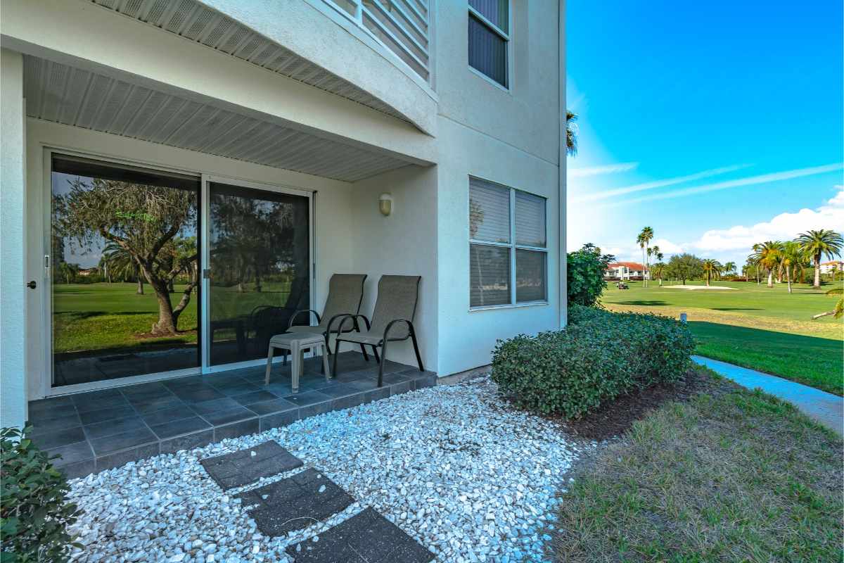 A ground-floor vacation rental patio in Isla Del Sol features outdoor seating and a direct view of a lush, sun-drenched golf course.