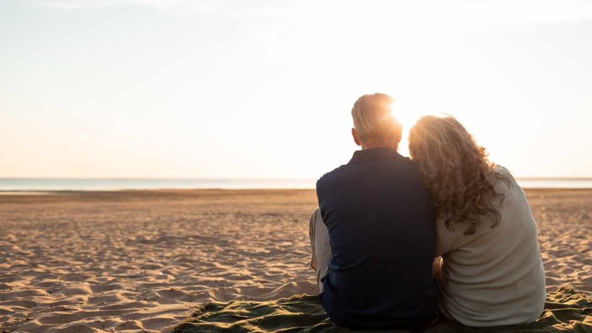 Couple sitting beach full shot